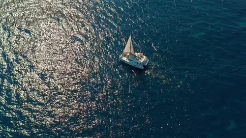 Vista aérea. Catamarán va por mar, la cámara se acerca y vuela sobre el barco, en la puesta de sol, hermoso