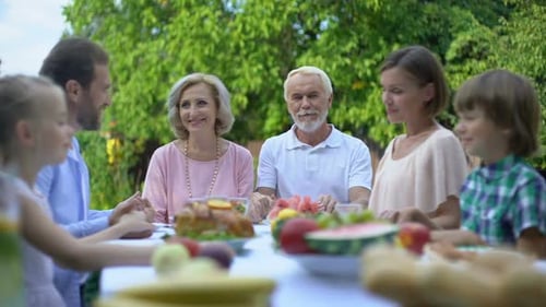 Family Holding Hands at Outdoor Dinner Table