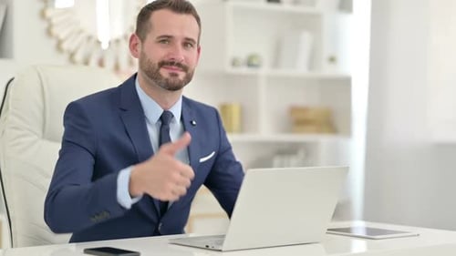 Man in Suit Giving Thumbs Up at Desk
