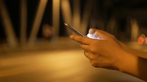 Hands Using Mobile Phone at Night in City