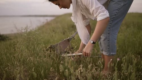 Young Brunette Girl in White Shirt and Jeans on Meado Near the Lake