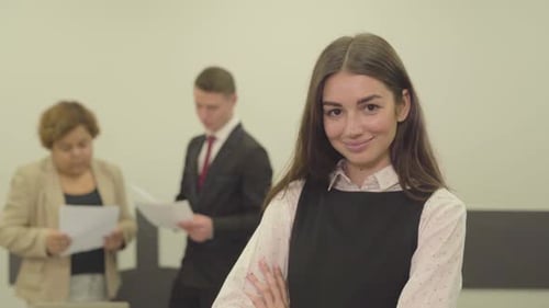 Young Woman Smiling in a Busy Office Environment
