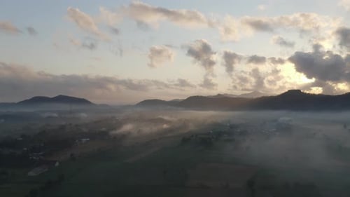 Cloudy Sky, Silhouetted Mountains and Thick Fog Covering Plains