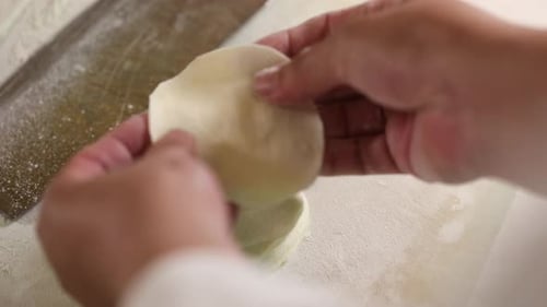 Professional chef neatly stacks prepared dumpling dough. Close up, top down shot.