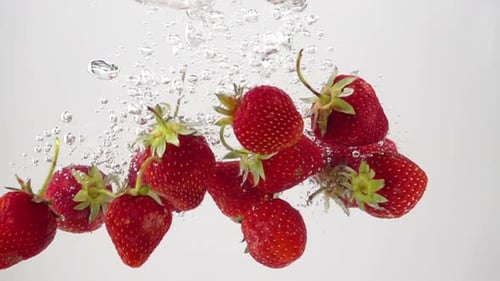 Des fraises mûres qui tombent dans l'eau