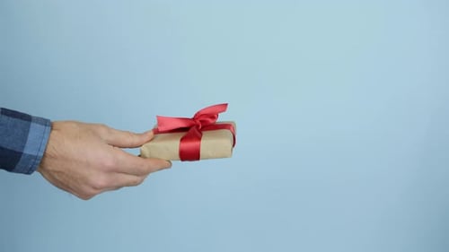Man hand is holding and showing gift box with red ribbon for St. Valentine's Day or Birthday.