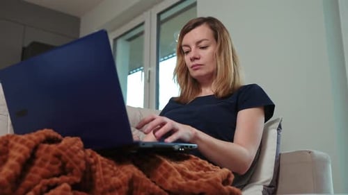 Woman Works on Laptop on Couch Indoors