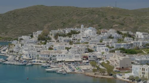 Inclinaison aérienne lente du village portuaire d'Adamas et des bateaux amarrés à un port de plaisance