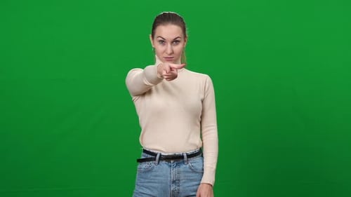 Ernsthafte strenge Frau zeigt auf Kamera stehend auf Greenscreen