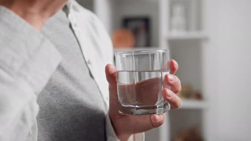 Person Taking a Pill with Glass of Water