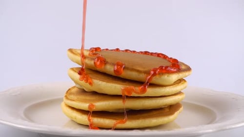 Pancakes Drenched in Strawberry Syrup on a Plate