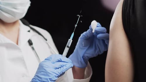 Doctor makes injection of vaccine for covid-19 coronavirus to patient in clinic