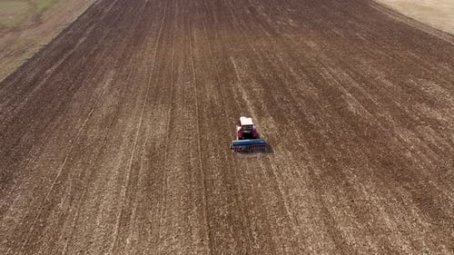 Tractor Tilling Brown Field in Rural Aerial Shot