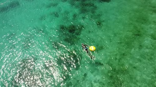Circling Aerial View of Freediver Floating in Crystal Clear Ocean Holding a Buoy