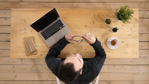 Man Cleaning Glasses While Working at Desk