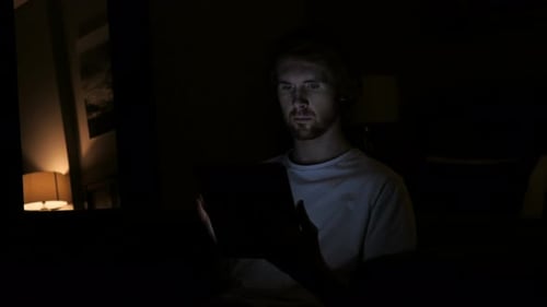 Man Using Tablet in Dark Room at Night