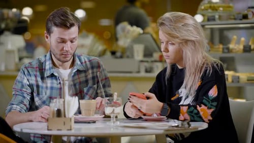 Couple Looks at Smartphone Together in Cafe