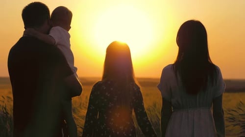 Family Silhouetted Enjoying Sunset in Rural Field