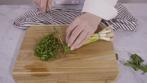 Step by step. Chopping organic green onions on a wood cutting board.