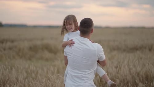 Father and Daughter Playing in Wheat Field at Sunset