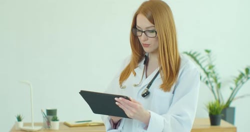 Woman Doctor Uses Tablet in Sunny Office