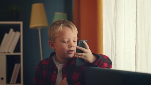 Smiling Blond Boy Using Smartphone at Home