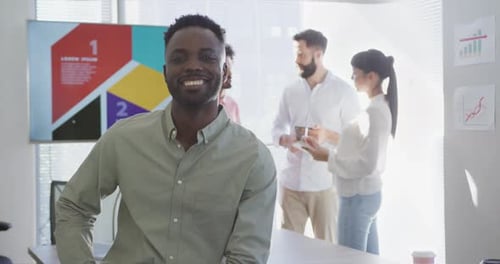 Portrait of happy african american businessman over diverse colleagues in office