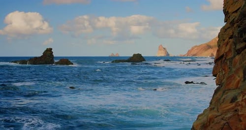 Waves Break on Rocks in a Blue Ocean