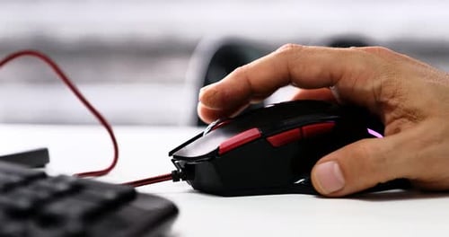Hand clicks wired gaming mouse on white desk