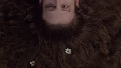 Man opens his eyes and flowers bloom on his hair. Growing flowers in the hair of a man with a pierce