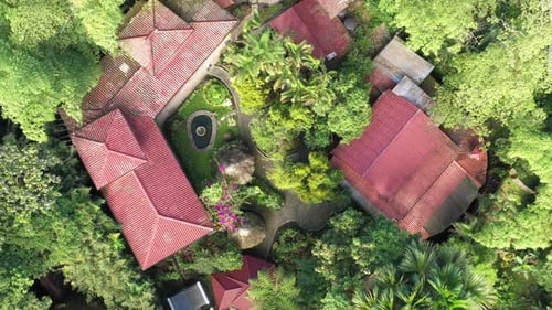 Blick aus der Vogelperspektive auf ein tropisches Resort mit roten Dächern, einem kleinen Springbrunnen und vielen Palmen