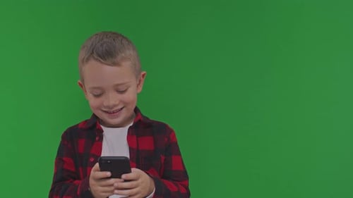 Smiling Child Using Smartphone Against Green Screen