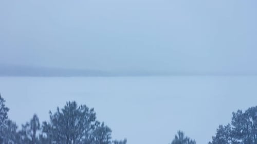 The peaceful blue snow covered landscape of Lapland, Finland - aerial rising
