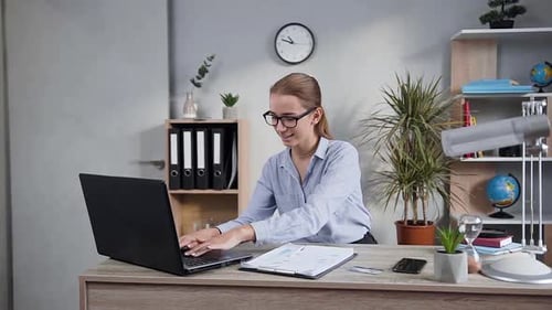 Young Woman Working at Desk on Laptop in Office