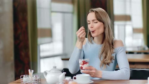 Pleasant Young Woman Smiling Eating Appetizing Creamy Dessert at Cafe