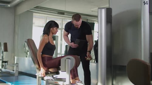 Fitness Trainer Helping Woman To Exercise at Gym