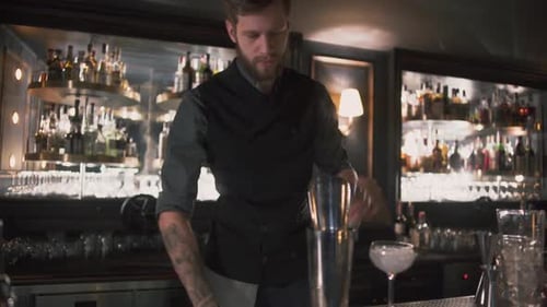 Bartender Mixing Drink Behind Bar at Night