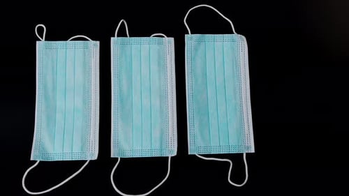 Hand Picking Up Surgical Masks on Black Surface
