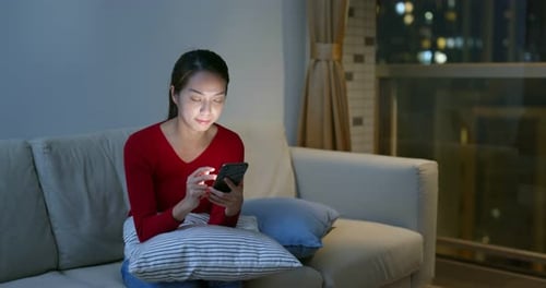 Woman Using Phone at Night in Apartment