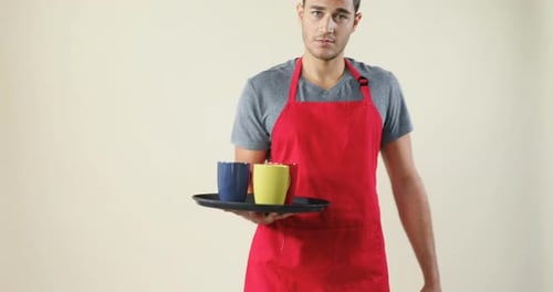 Young Man Holds Tray with Mugs and Smiles