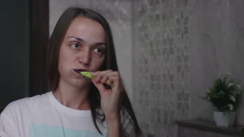 Woman Brushing Teeth in Bathroom Mirror