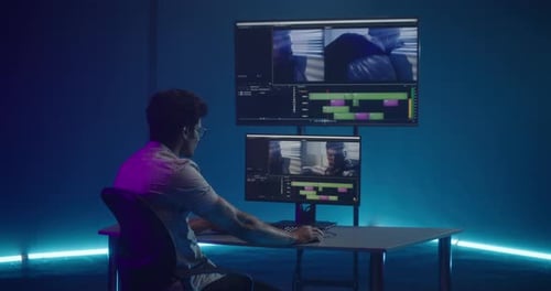 Young Adult Editing Video in Blue-lit Room