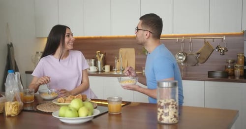 Couple Eating Breakfast and Talking in Kitchen