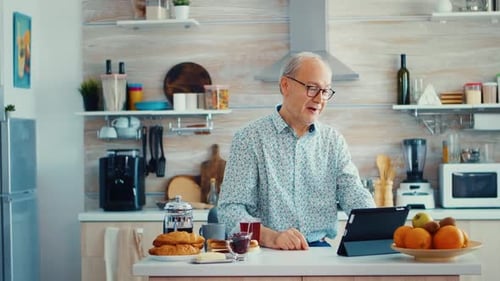 Senior Man Video Calling on Tablet in Kitchen