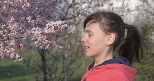 Girl with Allergies Sneezing by Pink Blossom Tree