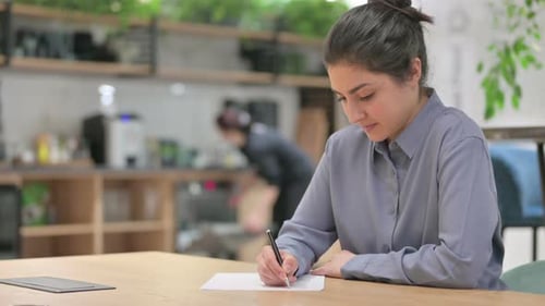 Woman Writing at Desk in Modern Workplace