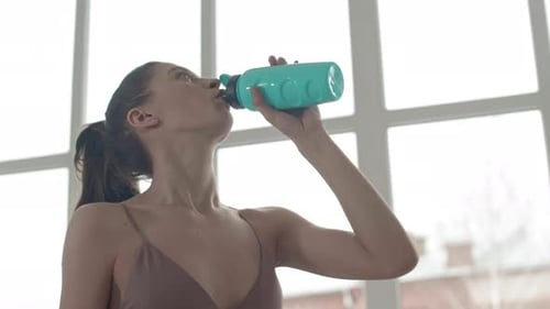 Woman Drinking Water After Workout Indoors
