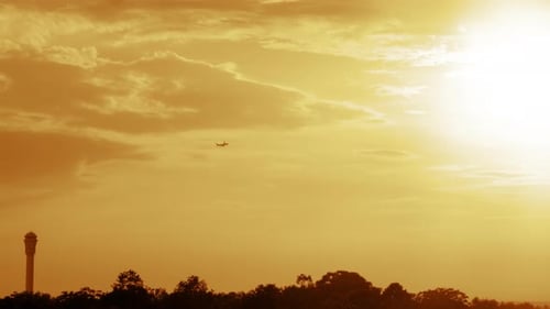 Airplane Flies Through Glowing Orange Sky at Sunset