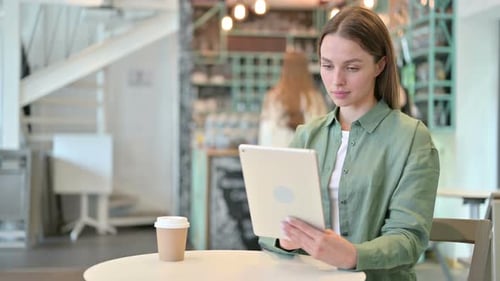 Serious Professional Woman Using Tablet in Cafe