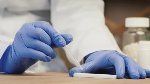 Lab Worker Drops Liquid Onto Medical Test Strip